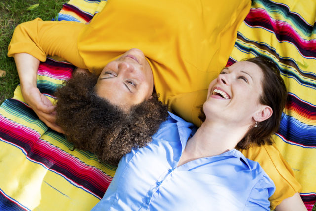 Two women laughing on a blanket