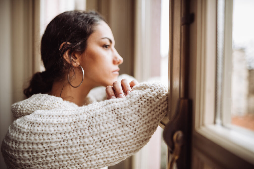 Pensive bisexual woman in front of the window