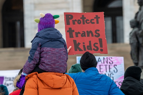 Protesters hold a sign that says "Protect Trans Kids"