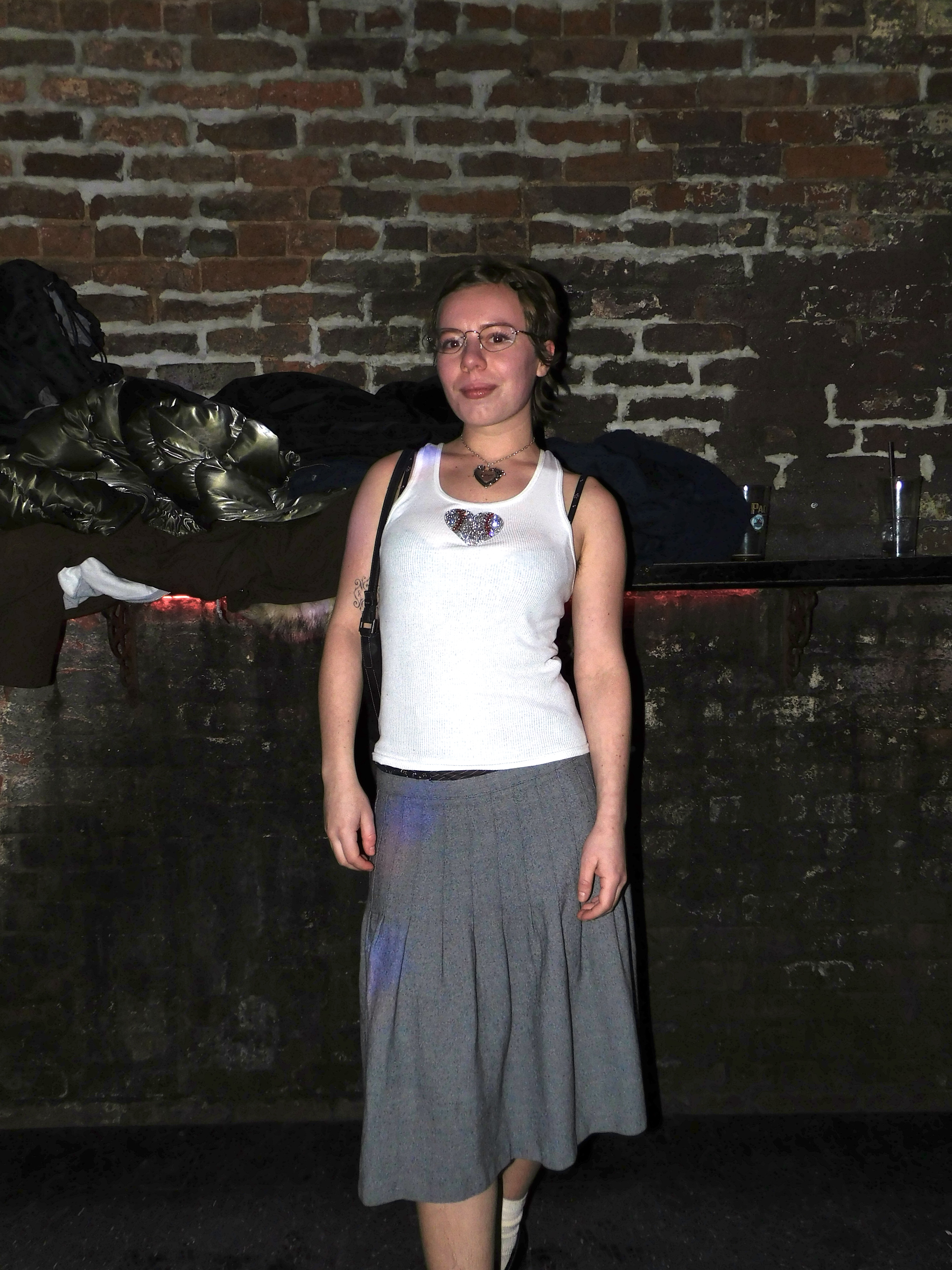 Effy in a whit tank and gray skirt