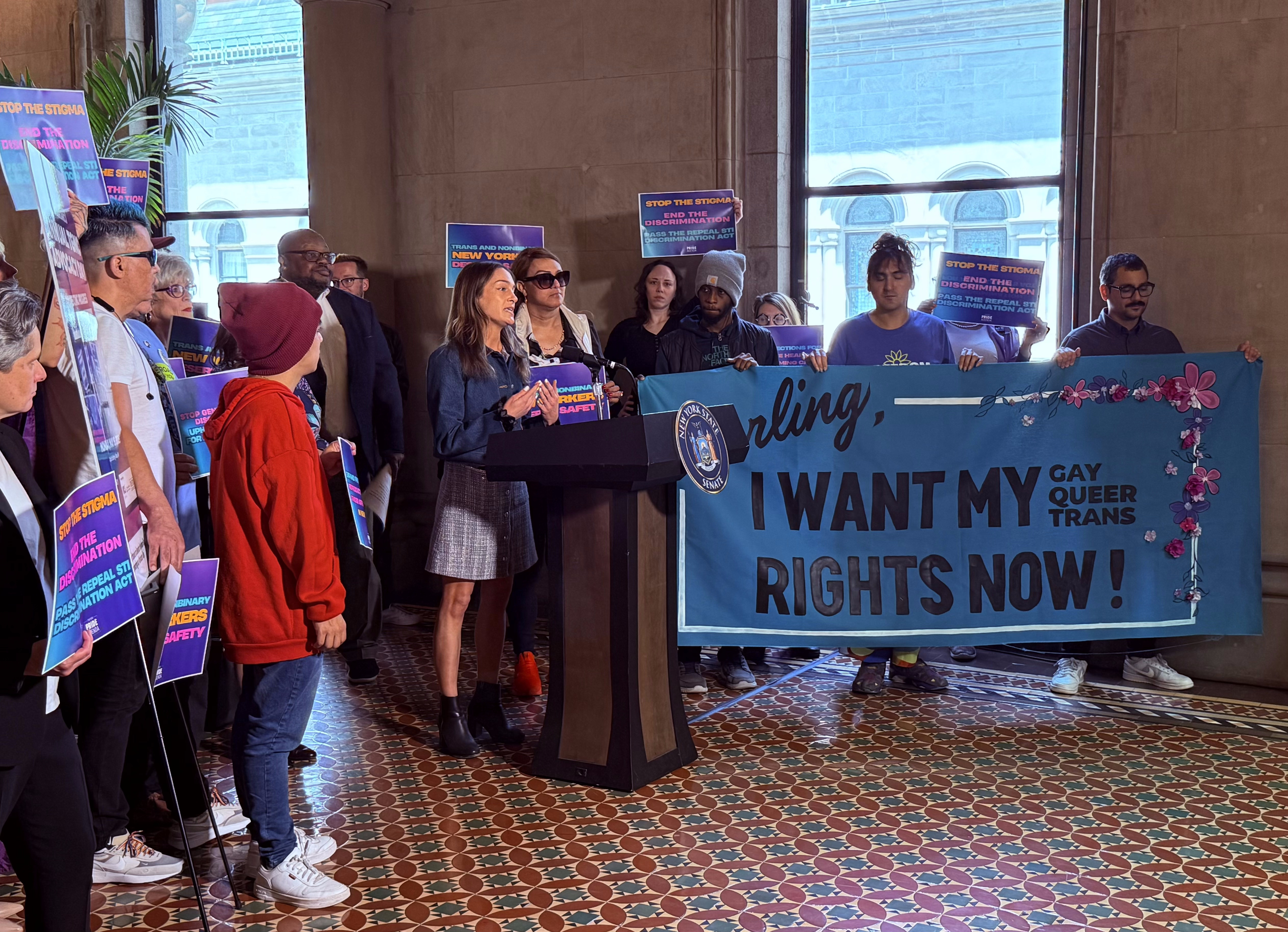 Members of NEW pride agenda and related coalitions pose with poster for the day's rally against continued LGBTQ+ discrimination in healthcare.