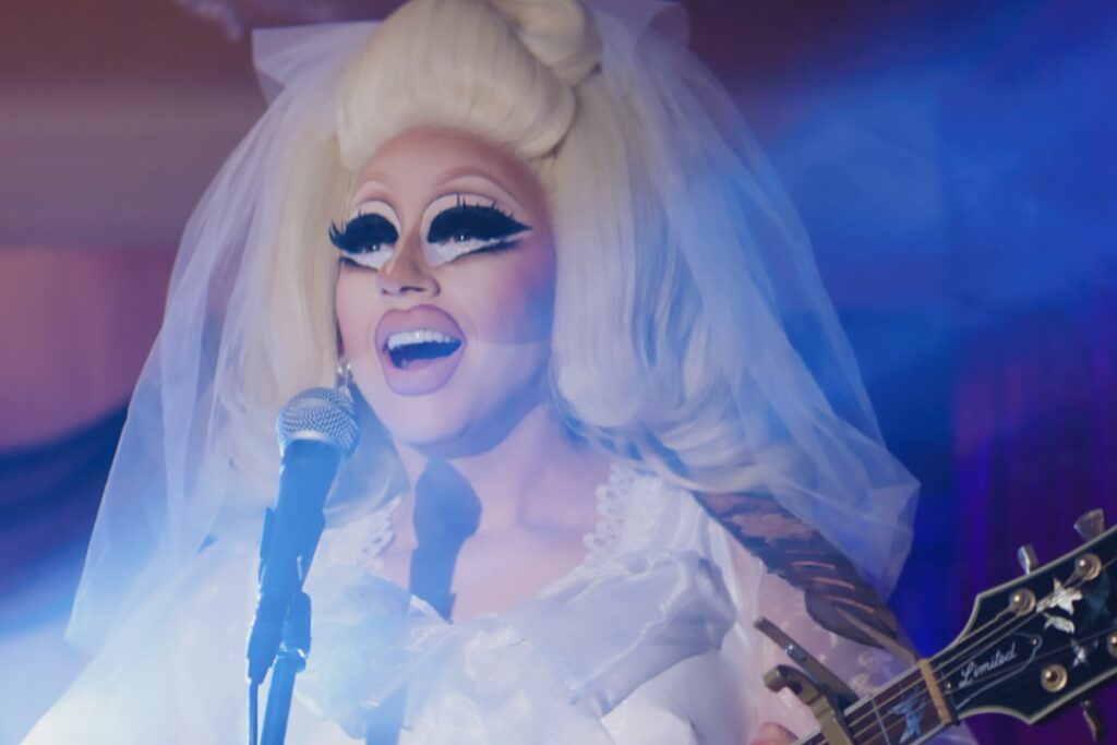 Trixie mattel dressed as a bride sings into a mic